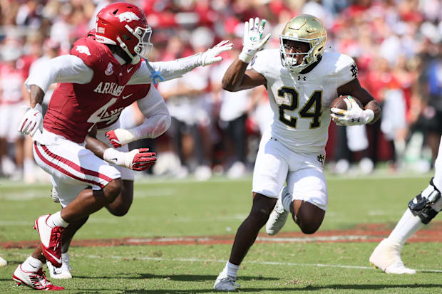 Notre Dame running back Jadarian Price rushes during the third quarter as Arkansas defensive back Jordan Young closes in.