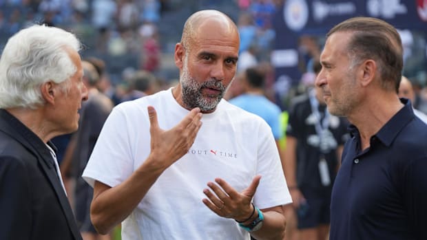 Manchester City head coach Pep Guardiola speaks with Marty Edelman and AC Milan owner Gerry Cardinale.