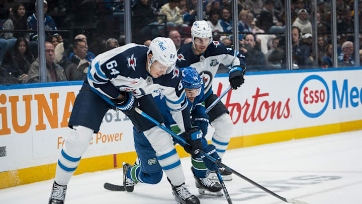 Nov 11, 2025; Vancouver, British Columbia, CAN; Winnipeg Jets defenseman Luke Schenn (5) watches as defenseman Logan Stanley (64) battles with Vancouver Canucks forward Kiefer Sherwood (44) in the second period at Rogers Arena. Mandatory Credit: Bob Frid-Imagn Images