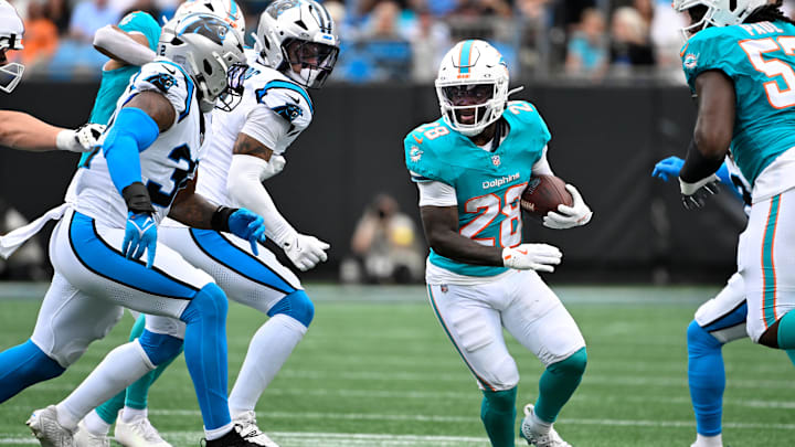 Oct 5, 2025; Charlotte, North Carolina, USA; Miami Dolphins running back De'Von Achane (28) runs as Carolina Panthers linebacker Trevin Wallace (32) defends in the first quarter at Bank of America Stadium. Mandatory Credit: Bob Donnan-Imagn Images