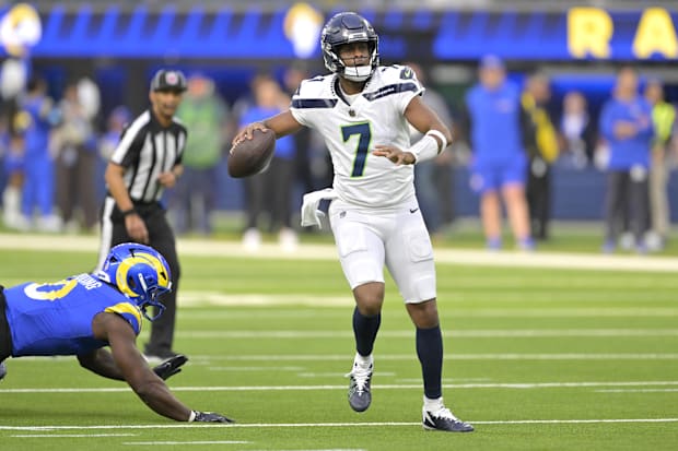 Seahawks quarterback Geno Smith scrambles away from Los Angeles Rams linebacker Byron Young