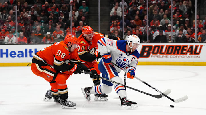 Apr 30, 2026; Anaheim, California, USA; Edmonton Oilers center Connor McDavid (97) handles the puck against Anaheim Ducks defenseman Pavel Mintyukov (98) and defenseman John Carlson (74) in the first period of game six of the first round of the 2026 Stanley Cup Playoffs at Honda Center. Mandatory Credit: Kirby Lee-Imagn Images