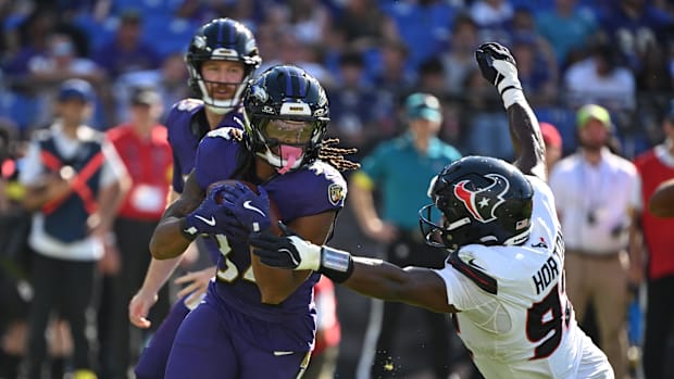Baltimore Ravens running back Keaton Mitchell runs for a gain past Houston Texans defensive end Dylan Horton