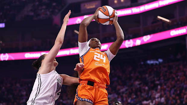 Connecticut Sun forward Aneesah Morrow controls a rebound, wearing an orange jersey with black and purple borders.