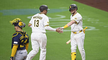 Sep 22, 2025; San Diego, California, USA; San Diego Padres third baseman Manny Machado (13) is congratulated by Jake Cronenworth (9) after scoring during the first inning against the Milwaukee Brewers at Petco Park. Mandatory Credit: Denis Poroy-Imagn Images