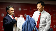 Oct 22, 2025; Los Angeles, CA, USA; Los Angeles Angels manager Kurt Suzuki, right, receives his jersey from general manager Perry Minasian during a press conference at Angel Stadium. Mandatory Credit: William Liang-Imagn Images