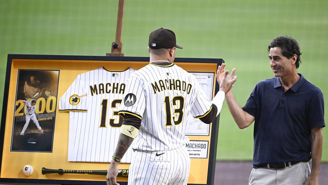Jul 8, 2025; San Diego, California, USA; San Diego Padres third baseman Manny Machado (13) shakes hands with general manager A.J. Preller after receiving commemorative memorabilia recognizing his 2,000th hit before a baseball game against the Arizona Diamondbacks at Petco Park. Mandatory Credit: Denis Poroy-Imagn Images