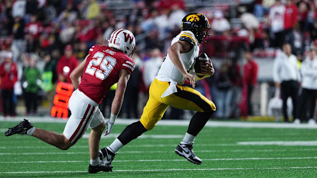 Iowa Hawkeyes quarterback Mark Gronowski runs the ball while being chased by Wisconsin Badgers safety Matthew Jung.