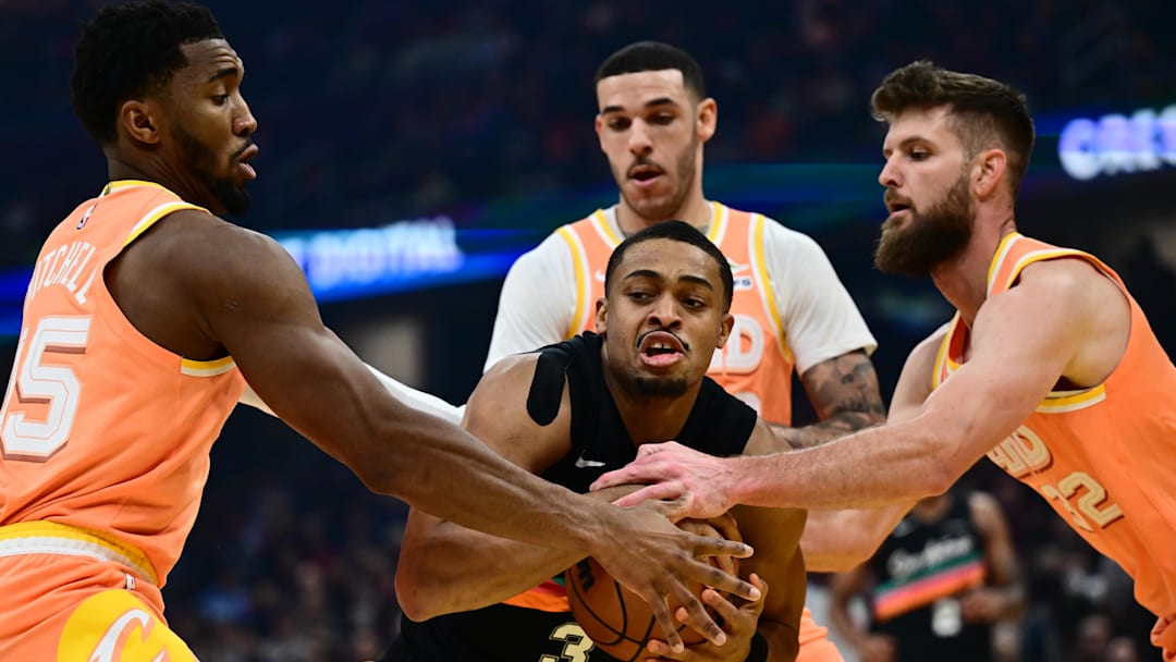 Dec 5, 2025; Cleveland, Ohio, USA; San Antonio Spurs forward Keldon Johnson (3) drives to the basket against Cleveland Cavaliers forward Dean Wade (32) and guard Donovan Mitchell (45) and guard Lonzo Ball (2) during the first half at Rocket Arena. Mandatory Credit: Ken Blaze-Imagn Images