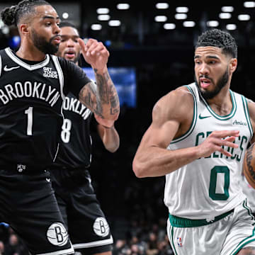 Mar 15, 2025; Brooklyn, New York, USA; Boston Celtics forward Jayson Tatum (0) drives past Brooklyn Nets guard D'Angelo Russell (1) during the second half at Barclays Center. Mandatory Credit: John Jones-Imagn Images