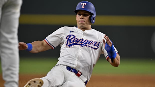 Texas Rangers center fielder Sam Haggerty slides into base while wearing a white uniform and blue helmet