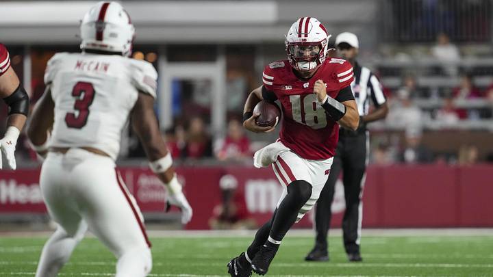 Aug 28, 2025; Madison, Wisconsin, USA;  Wisconsin Badgers quarterback Danny O'Neil (18) rushes with the football as Miami (OH) RedHawks linebacker Malcolm McCain (3) defends during the third quarter at Camp Randall Stadium. Mandatory Credit: Jeff Hanisch-Imagn Images