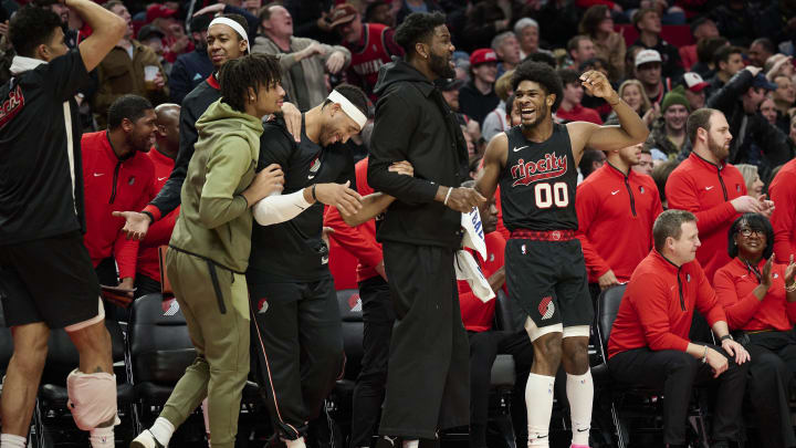 Dec 29, 2023; Portland, Oregon, USA; Portland Trail Blazers guard Scoot Henderson (00), right, reacts with teammates, from left, guard Shaedon Sharpe (17), forward Ish Wainright (23), and center Deandre Ayton (2) after a play during the second half against the San Antonio Spurs at Moda Center. Mandatory Credit: Troy Wayrynen-USA TODAY Sports