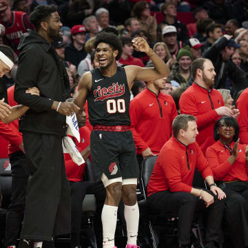 Dec 29, 2023; Portland, Oregon, USA; Portland Trail Blazers guard Scoot Henderson (00), right, reacts with teammates, from left, guard Shaedon Sharpe (17), forward Ish Wainright (23), and center Deandre Ayton (2) after a play during the second half against the San Antonio Spurs at Moda Center. Mandatory Credit: Troy Wayrynen-USA TODAY Sports