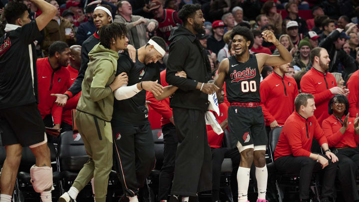 Dec 29, 2023; Portland, Oregon, USA; Portland Trail Blazers guard Scoot Henderson (00), right, reacts with teammates, from left, guard Shaedon Sharpe (17), forward Ish Wainright (23), and center Deandre Ayton (2) after a play during the second half against the San Antonio Spurs at Moda Center. Mandatory Credit: Troy Wayrynen-USA TODAY Sports