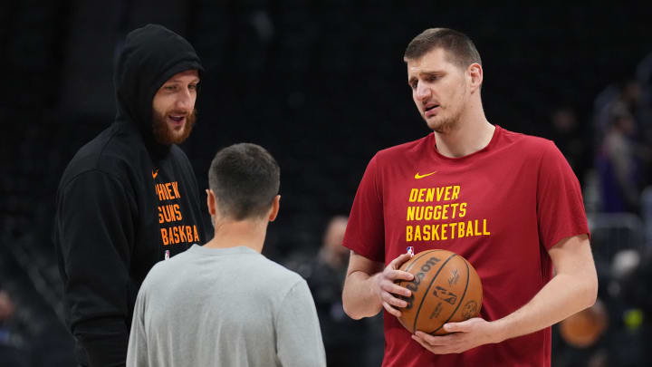 Denver Nuggets center Nikola Jokic (15) (right) and Phoenix Suns center Jusuf Nurkic (20) left speak to Nuggets assistant coach Ognjen Stojakovic before a game at Ball Arena. 