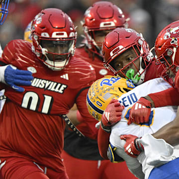 Nov 23, 2024; Louisville, Kentucky, USA;  Louisville Cardinals linebacker Stanquan Clark (6) and linebacker TJ Quinn (34) tackle Pittsburgh Panthers running back Desmond Reid (0) during the first half at L&N Federal Credit Union Stadium. Mandatory Credit: Jamie Rhodes-Imagn Images