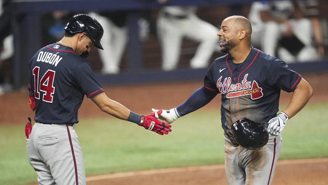 May 20, 2026; Miami, Florida, USA;  Atlanta Braves designated hitter Dominic Smith, right, celebrates scoring a run on a throwing error by Miami Marlins center fielder Esteury Ruiz (not pictured) with shortstop Mauricio Dubon (14) at loanDepot Park. Mandatory Credit: Jim Rassol-Imagn Images