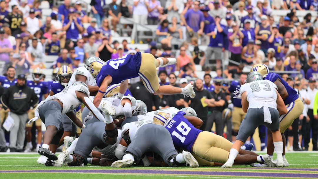 Sep 7, 2024; Seattle, Washington, USA; Washington Huskies linebacker Carson Bruener (42) jumps over the line on a fourth and short Eastern Michigan Eagles down during the second half at Alaska Airlines Field at Husky Stadium. Mandatory Credit: Steven Bisig-Imagn Images