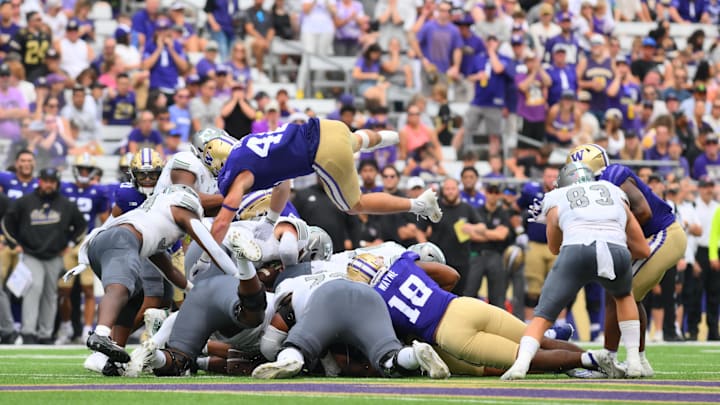 Sep 7, 2024; Seattle, Washington, USA; Washington Huskies linebacker Carson Bruener (42) jumps over the line on a fourth and short Eastern Michigan Eagles down during the second half at Alaska Airlines Field at Husky Stadium. Mandatory Credit: Steven Bisig-Imagn Images