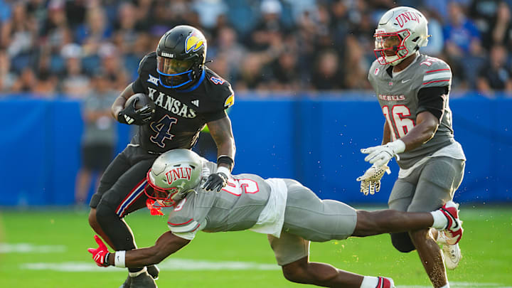 Sep 13, 2024; Kansas City, Kansas, USA; Kansas Jayhawks running back Devin Neal (4) runs the ball against UNLV Rebels defensive back Jett Elad (9) and linebacker Mani Powell (16) during the first half at Children's Mercy Park.