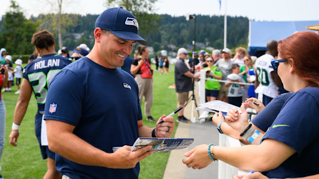 Seattle Seahawks head coach Mike Macdonald signs autographs after training camp