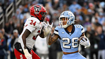 Nov 30, 2024; Chapel Hill, North Carolina, USA; North Carolina Tar Heels running back Omarion Hampton (28) with the ball as North Carolina State Wolfpack linebacker Kamal Bonner (34) defends in the first quarter at Kenan Memorial Stadium. Mandatory Credit: Bob Donnan-Imagn Images