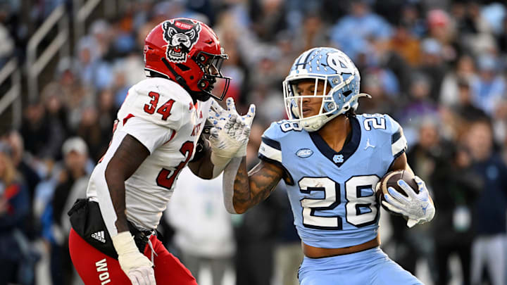 North Carolina Tar Heels running back Omarion Hampton with the ball as North Carolina State Wolfpack linebacker Kamal Bonner