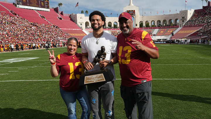 Nov 30, 2024; Los Angeles, California, USA; Chicago Bears quarterback Caleb Williams (center) holds Heisman Trophy and poses with father Carl Williams (right) and mother Dayne Price Nov 30, 2024; Los Angeles, California, USA; Chicago Bears quarterback Caleb Williams (center) holds Heisman Trophy and poses with father Carl Williams (right) and mother Dayne Price
