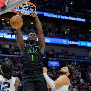 Dec 19, 2023; New Orleans, Louisiana, USA; New Orleans Pelicans forward Zion Williamson (1) dunks against Memphis Grizzlies guard Ja Morant (12) and forward David Roddy (21) during the second half at the Smoothie King Center. 