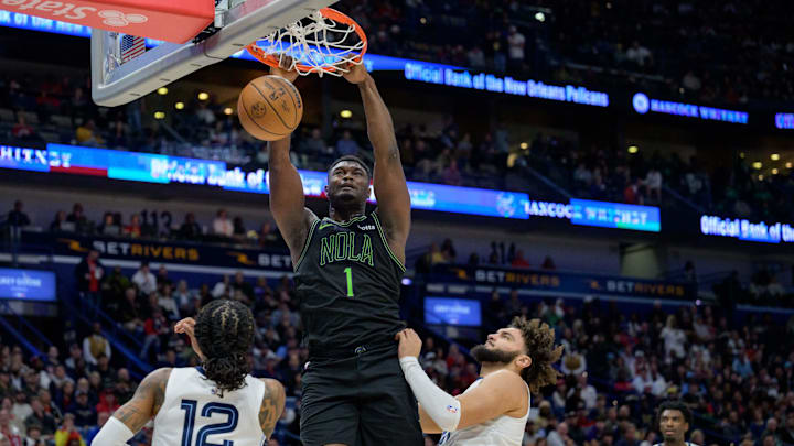 Dec 19, 2023; New Orleans, Louisiana, USA; New Orleans Pelicans forward Zion Williamson (1) dunks against Memphis Grizzlies guard Ja Morant (12) and forward David Roddy (21) during the second half at the Smoothie King Center. 