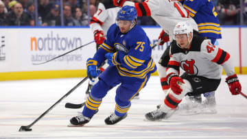 Mar 29, 2024; Buffalo, New York, USA;  Buffalo Sabres defenseman Connor Clifton (75) controls the puck as New Jersey Devils center Curtis Lazar (42) defends during the third period at KeyBank Center. Mandatory Credit: Timothy T. Ludwig-USA TODAY Sports