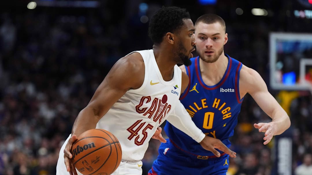 Feb 9, 2026; Denver, Colorado, USA; Cleveland Cavaliers guard Donovan Mitchell (45) dribbles past Denver Nuggets guard Christian Braun (0) in the first quarter at Ball Arena.