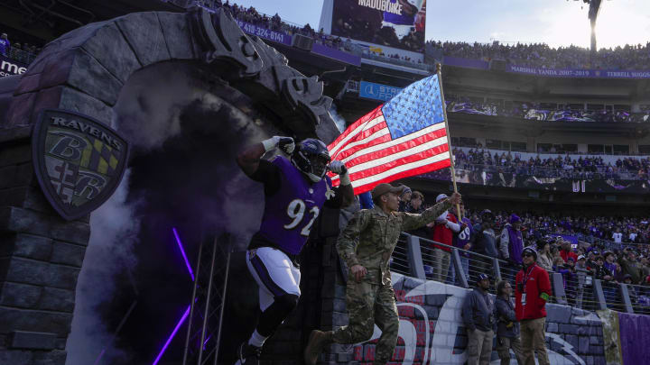 Baltimore Ravens defensive tackle Justin Madubuike (92) takes the field with a military service member before a game against the Cleveland Browns at M&T Bank Stadium. 