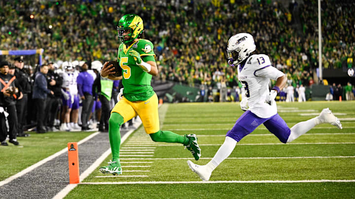 Dec 20, 2025; Eugene, OR, USA; Oregon Ducks quarterback Dante Moore (5) rushes for a touchdown as James Madison Dukes safety Tyler Brown (13) defends during the first quarter at Autzen Stadium.