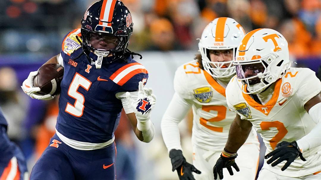 Illinois running back Ca'Lil Valentine (5) runs the ball ahead of Tennessee defensive back Andre Turrentine (2) and linebacker Jadon Perlotte (27) for a first down in the first quarter of the Music City Bowl against Tennessee in an NCAA football game on Dec. 30, 2025, in Nashville, Tennessee.
