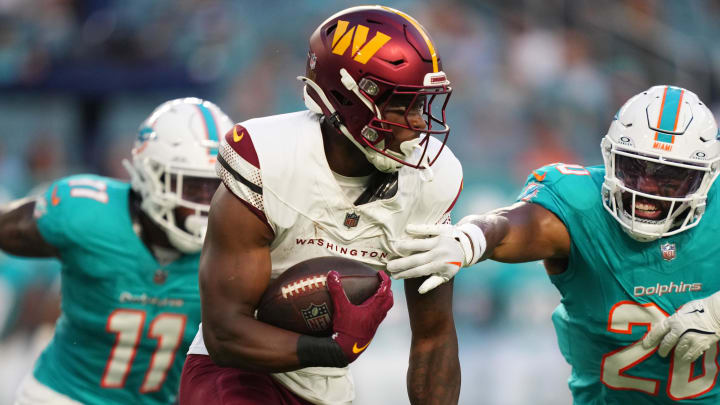 Aug 17, 2024; Miami Gardens, Florida, USA;  Washington Commanders running back Brian Robinson Jr. (8) looks for running room as Miami Dolphins linebacker Jordyn Brooks (20) closes in during the first quarter at Hard Rock Stadium. Mandatory Credit: Jim Rassol-USA TODAY Sports