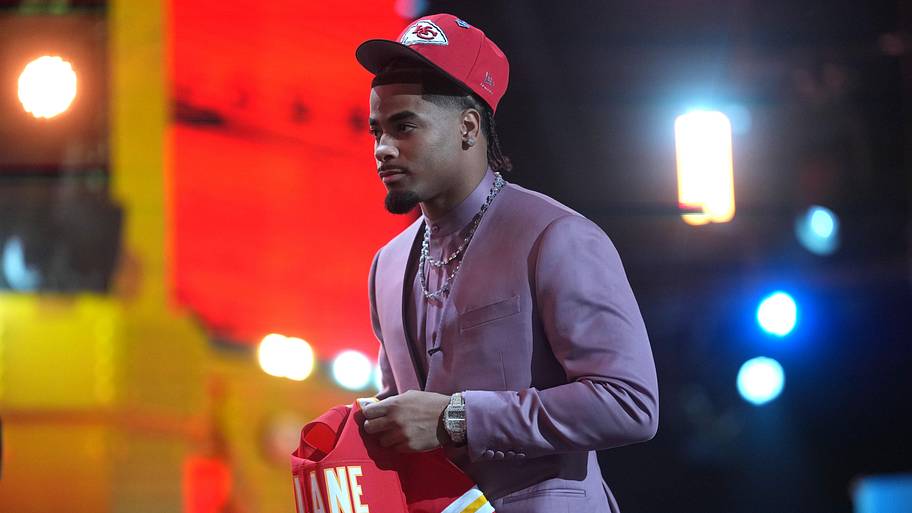 Mansoor Delane holds a Chiefs jersey on the stage on draft night.