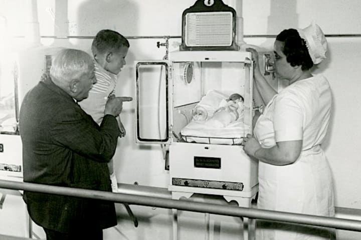 Martin Couney and his daughter Hildegarde, a nurse, show a young boy an infant in an incubator.
