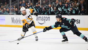 Jan 25, 2025; Seattle, Washington, USA; Pittsburgh Penguins defenseman Kris Letang (58) passes the puck past Seattle Kraken left wing Brandon Tanev (13) during the second period at Climate Pledge Arena. Mandatory Credit: Steven Bisig-Imagn Images
