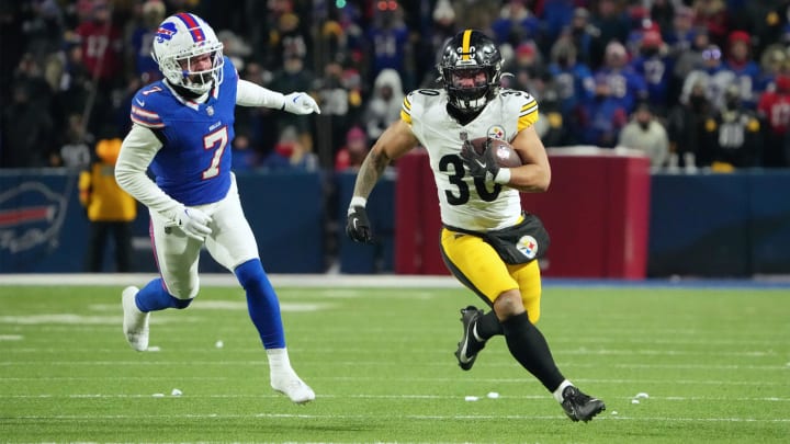 Jan 15, 2024; Orchard Park, New York, USA; Pittsburgh Steelers running back Jaylen Warren (30) runs the ball pressured by Buffalo Bills cornerback Taron Johnson (7) in the first half in a 2024 AFC wild card game at Highmark Stadium. Mandatory Credit: Kirby Lee-USA TODAY Sports