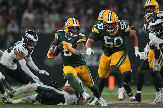 Green Bay Packers running back Josh Jacobs runs the ball in a green jersey.