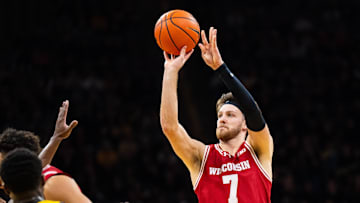 Feb 8, 2025; Iowa City, Iowa, USA; Wisconsin Badgers forward Carter Gilmore (7) shoots a three point basket against Iowa Hawkeyes forward Seydou Traore (7) during the first half at Carver-Hawkeye Arena. Mandatory Credit: Dylan Widger-Imagn Images