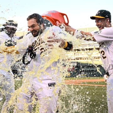 Sep 2, 2024; Oakland, California, USA; Oakland Athletics outfielder Lawrence Butler (left) and shortstop Max Schuemann (right) douse catcher Shea Langelier (center) after his walk-off home run against the Seattle Mariners at Oakland-Alameda County Coliseum. Mandatory Credit: Eakin Howard-USA TODAY Sports