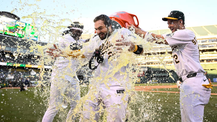 Sep 2, 2024; Oakland, California, USA; Oakland Athletics outfielder Lawrence Butler (left) and shortstop Max Schuemann (right) douse catcher Shea Langelier (center) after his walk-off home run against the Seattle Mariners at Oakland-Alameda County Coliseum. Mandatory Credit: Eakin Howard-USA TODAY Sports