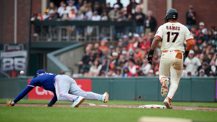 Apr 27, 2025; San Francisco, California, USA; Texas Rangers first baseman Jake Burger (21) extends for an errant throw as San Francisco Giants outfielder Heliot Ramos (17) runs toward first base during the ninth inning at Oracle Park. Mandatory Credit: Robert Edwards-Imagn Images Apr 27, 2025; San Francisco, California, USA; Texas Rangers first baseman Jake Burger (21) extends for an errant throw as San Francisco Giants outfielder Heliot Ramos (17) runs toward first base during the ninth inning at Oracle Park. Mandatory Credit: Robert Edwards-Imagn Images