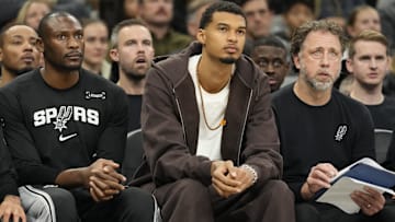 Dec 2, 2025; San Antonio, Texas, USA; San Antonio Spurs forward Victor Wembanyama (1) along with center Bismack Biyombo (18) and assistant coach Matt Nielsen