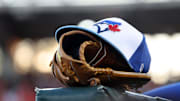 A detail view of a Toronto Blue Jays hat and glove against the Baltimore Orioles at Ed Smith Stadium in 2025.