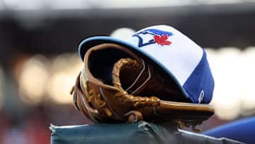 A detail view of a Toronto Blue Jays hat and glove against the Baltimore Orioles at Ed Smith Stadium in 2025.