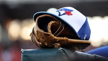Mar 18, 2025; Sarasota, Florida, USA;  A detail view of a Toronto Blue Jays hat and glove against the Baltimore Orioles at Ed Smith Stadium.